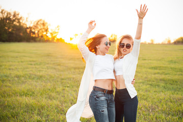 Two pretty young women are waving hands under the sunlight in the evening.Best friends