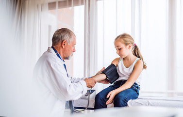 Senior doctor checking a small girl in his office.