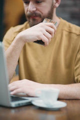 Man using laptop and smart phone while sitting in cafe. New technologies concept