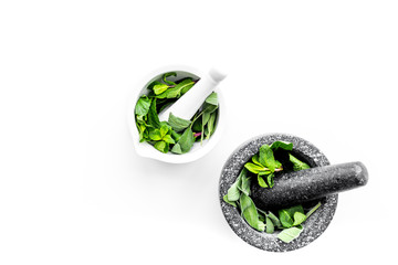 Phytotherapy. Herbs in mortar bowl on white background top view copy space