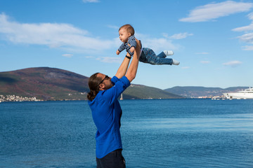 father raises his son in his arms to the sea