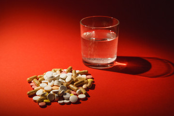 Medication white colorful tablets arranged abstract on dark red color background. Capsule vial glass of water pills design. Health treatment choice healthy lifestyle concept. Copy space advertisement.