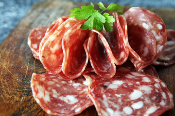thinly sliced salami on a wooden texture on the background.