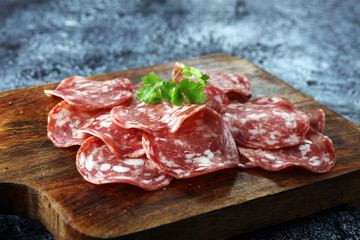 thinly sliced salami on a wooden texture on the background.