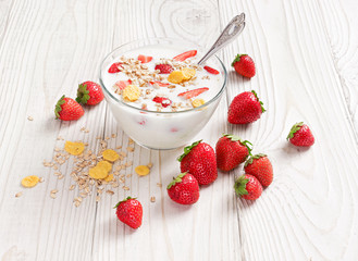 Bowl of homemade yogurt with muesli and fresh strawberry on wooden table. Fresh yogurt. Healthy food concept. High resolution product.