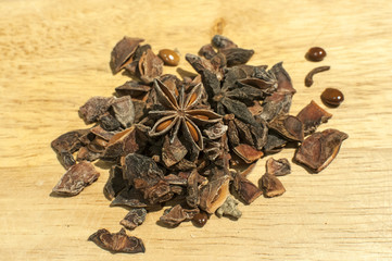 A pile of broken star anise seed as spice closeup on wooden board background