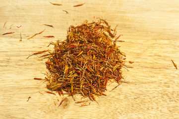 Fototapeta premium A pile of dry delicate saffron threads, plucked from crocus flowers closeup on wooden board background