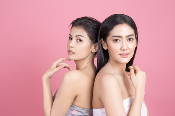 Portrait of Two Beautiful Asian Woman. Beautiful Woman looking to camera.  People with Youth and Skin Care Concept. isolated on pink background.