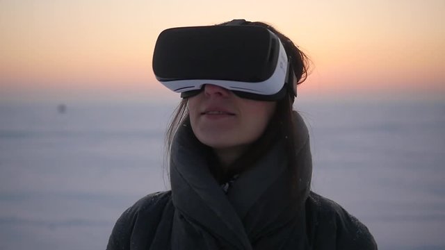 The girl uses virtual reality glasses in the winter on the street