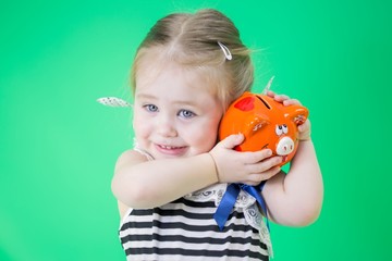 Happy cute little girl with piggy bank