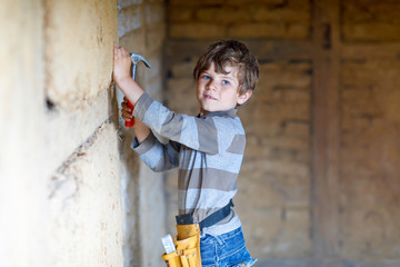 Little kid boy helping with toy tools on construciton site.