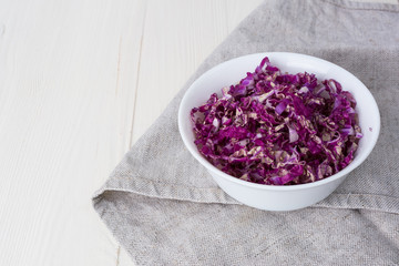 Obraz na płótnie Canvas sliced ​​red chinese cabbage in a white cup on a white wooden background