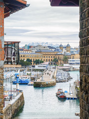 San Sebastian (Donostia) cityscape in cloudy winter day with the snowy mountains on horizon.