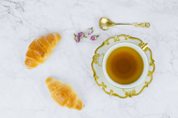Breakfast table with cup of tea and croissant