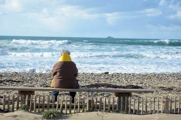 Femme assise sur un banc regardant la mer 