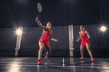 Fototapeta na wymiar Young women playing badminton at gym