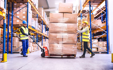 Warehouse workers pulling a pallet truck. - obrazy, fototapety, plakaty