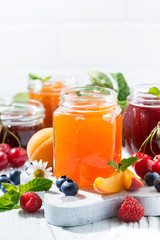 assortment of sweet jams and seasonal fruits on white background, closeup vertical