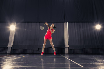 Fototapeta na wymiar Young woman playing badminton at gym