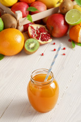 A glass of juice with a straw from different fruits