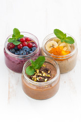 desserts with fresh berries, fruit and chocolate on white table, vertical, top view
