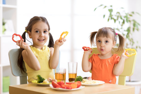 happy preschooler kids eating healthy food in kindergarten or at home