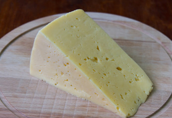 a piece of young cheese on a wooden blackboard close-up