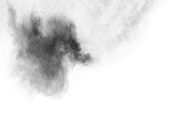 Black powder explosion against white background.The particles of charcoal splatted on white background. Closeup of black dust particles explode isolated on white background.