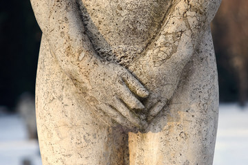 Rzeźba z kamienia, kobiece genitalia przykryte rekami,  zbliżenie