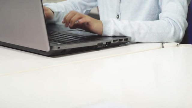 Close up of a pretty little Asian girl typing on the laptop