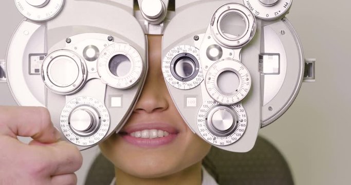 In an optical store, a boy makes a medical examination with the professional equipment to see how many dioptres are missing from sight. Concept of: medical examination, optic, eyes.