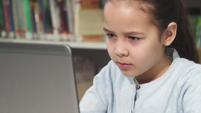 Cute little girl concentrating using her laptop