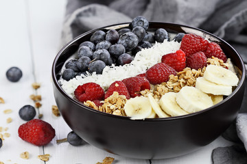 Healthy Breakfast Buddha Bowl with berries, coconut, bananas and granola.