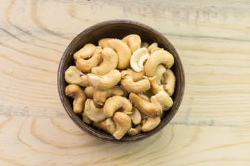 Bowl with cashew nuts on wooden table. Delicacies 