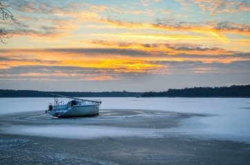 Afternoon winter landscape. Boat on a frozen lake.