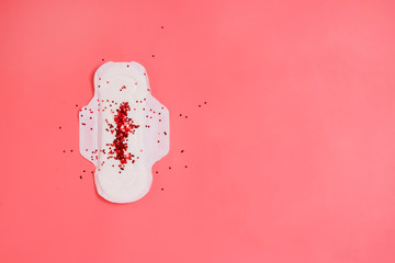 White sanitary pad with red sparkling glitter on it, woman health or body positive concept. Pink background. Copyspace