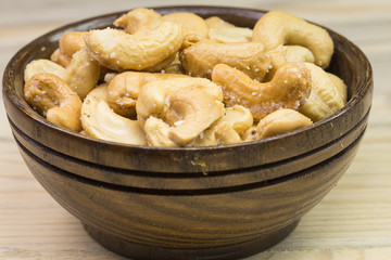 Bowl with cashew nuts on wooden table. Delicacies 