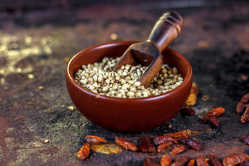 spices - coriander seeds in a brown bowl with the wooden scoop.