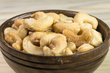 Bowl with cashew nuts on wooden table. Delicacies 