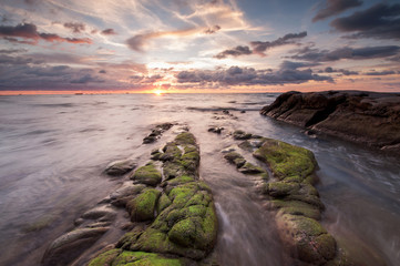 Fototapeta na wymiar colorful sunset sky with rocks covered by green moss at Kudat Sabah Malaysia.