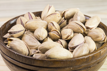 wooden bowl of pistachios on wooden background 