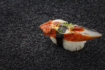 Japanese cuisine. Eel sushi nigiri on a sesame backround.