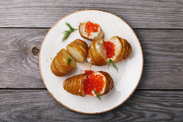 Cooking ourselves, baked potatoes with Dutch sauce and red caviar on a wooden table, top view