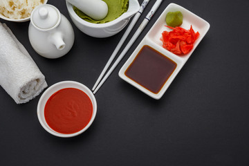 Set for sushi. Sauces , ginger , wasabi, chopsticks over dark background.