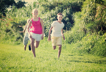 Group of laughing children having fun together outdoors running