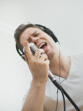 Handsome man recording a song. Focused on the microphone. Space for your text.