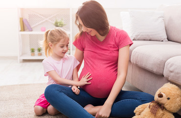 Little girl touching her pregnant mother belly