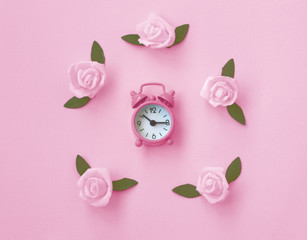 gentle pink paper texture background with alarm clock, rose