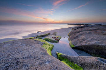 scenic view of sunset seascape with natural coastal rocks as foreground.