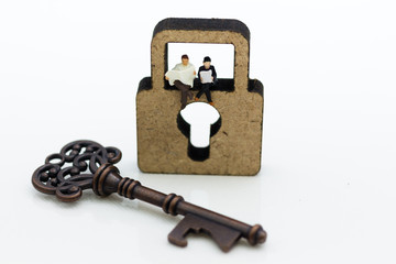 Miniature people: Businessmen sitting on the master key and reading newspaper. Image use for key...